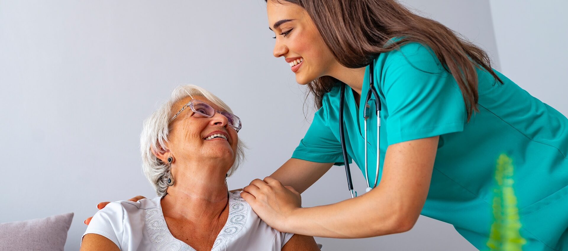 Smiling elderly female patient looking up at smiling female doctor